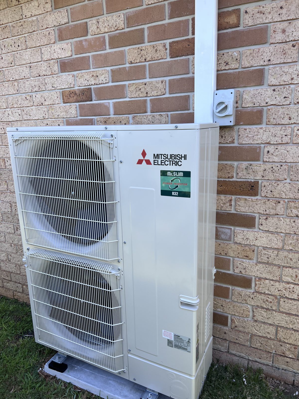 Large twin-fan Mitsubishi ducted outdoor unit installed on a slab